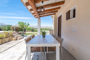 A covered outdoor dining area with a table and chairs, a potted plant, and a view of the mountains. - Villa 'Negri' with Private Pool, Wi-Fi and Air Conditioning (Illes Balears)