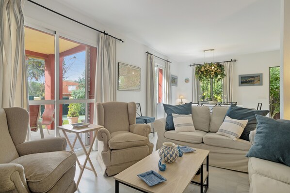 A living room with a sofa, armchairs, a coffee table, and a view of the outside.