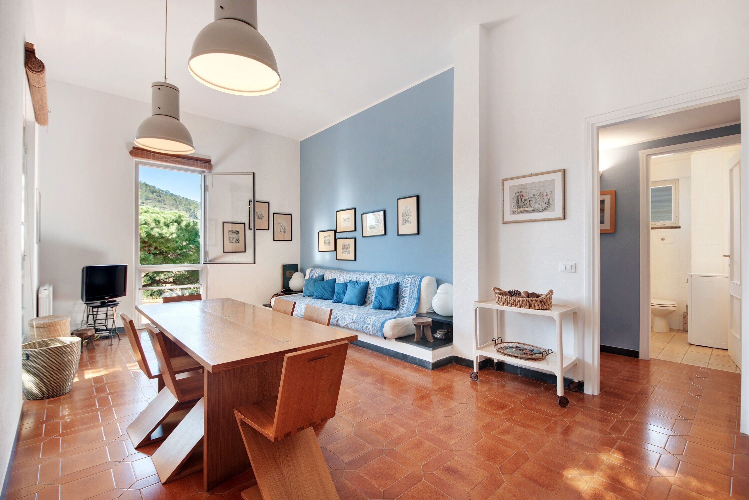 A modern interior with a dining area, sofa, and artwork on the walls.