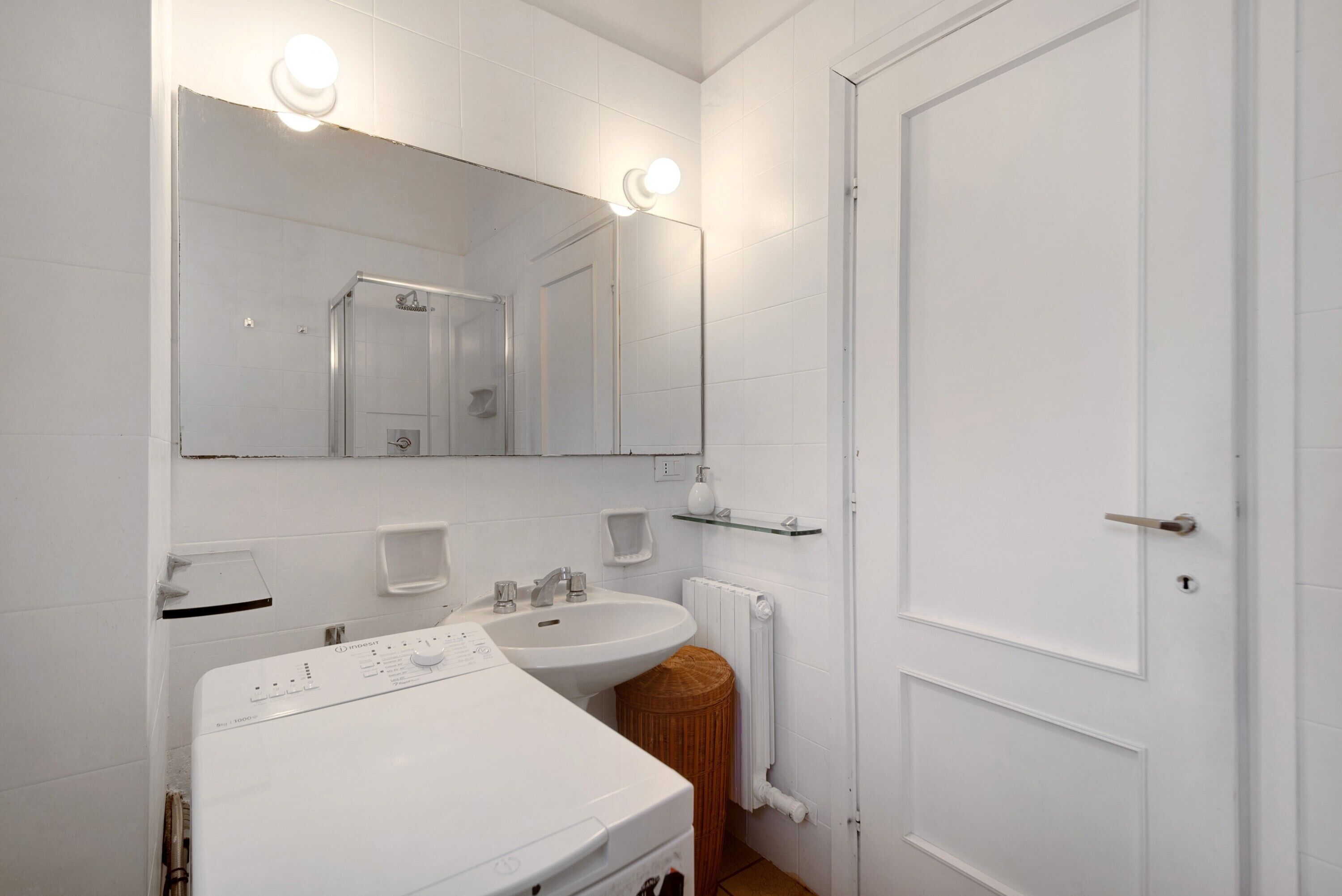 A bathroom with a white sink, mirror, and a white door.