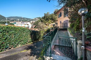 Un quartier résidentiel avec un chemin pavé, un portail en métal et un immeuble doté d’un balcon.