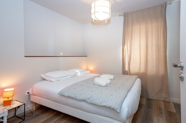 A neatly made bed with a striped blanket, a bedside lamp, and a wall-mounted light fixture.