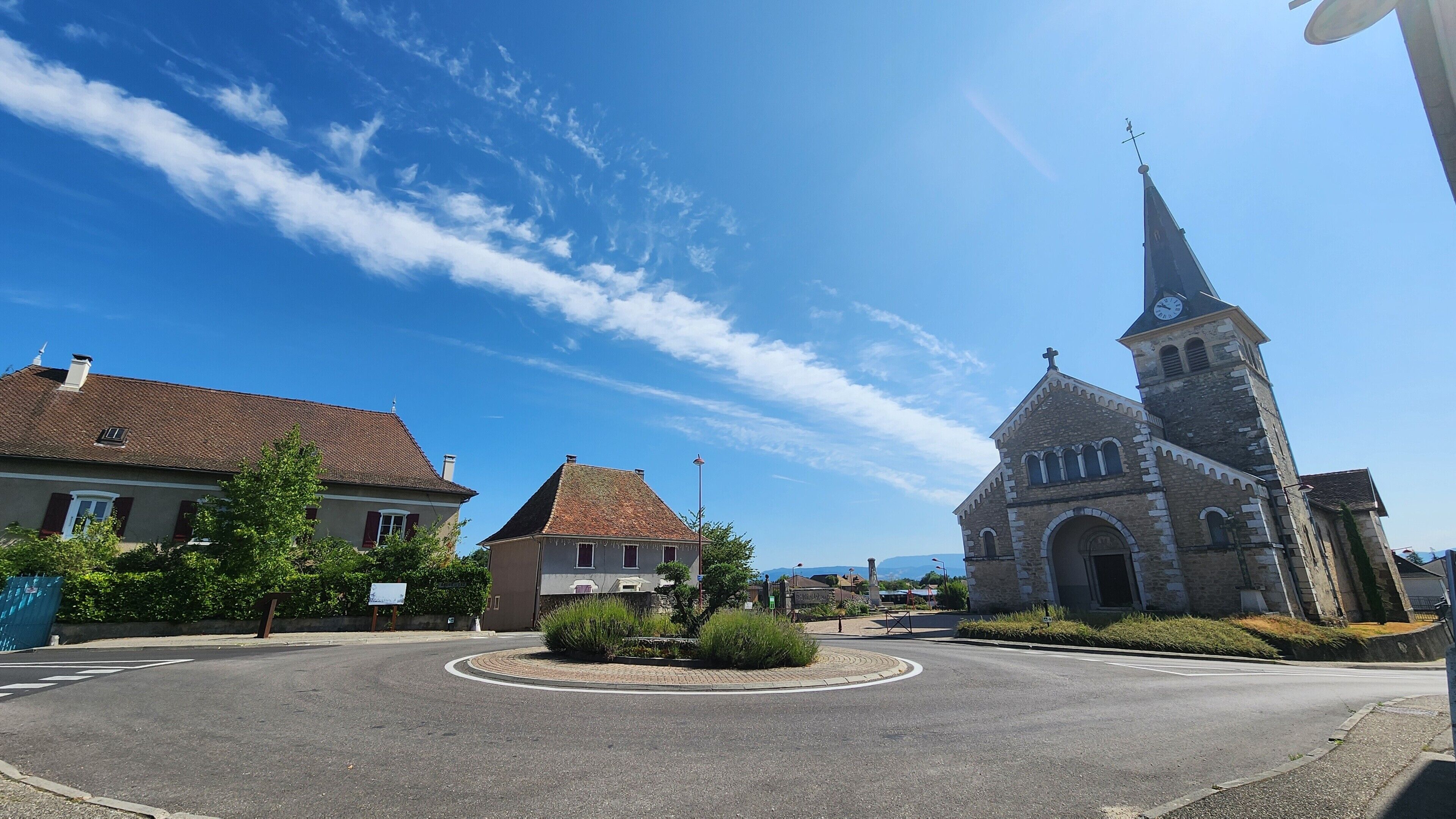 A roundabout with a church featuring a tall steeple and clock tower.