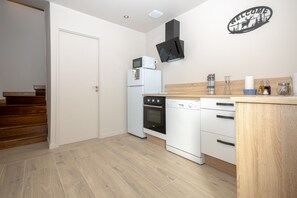 A kitchen with a microwave, oven, and dishwasher, wooden flooring, and a welcome sign on the wall.