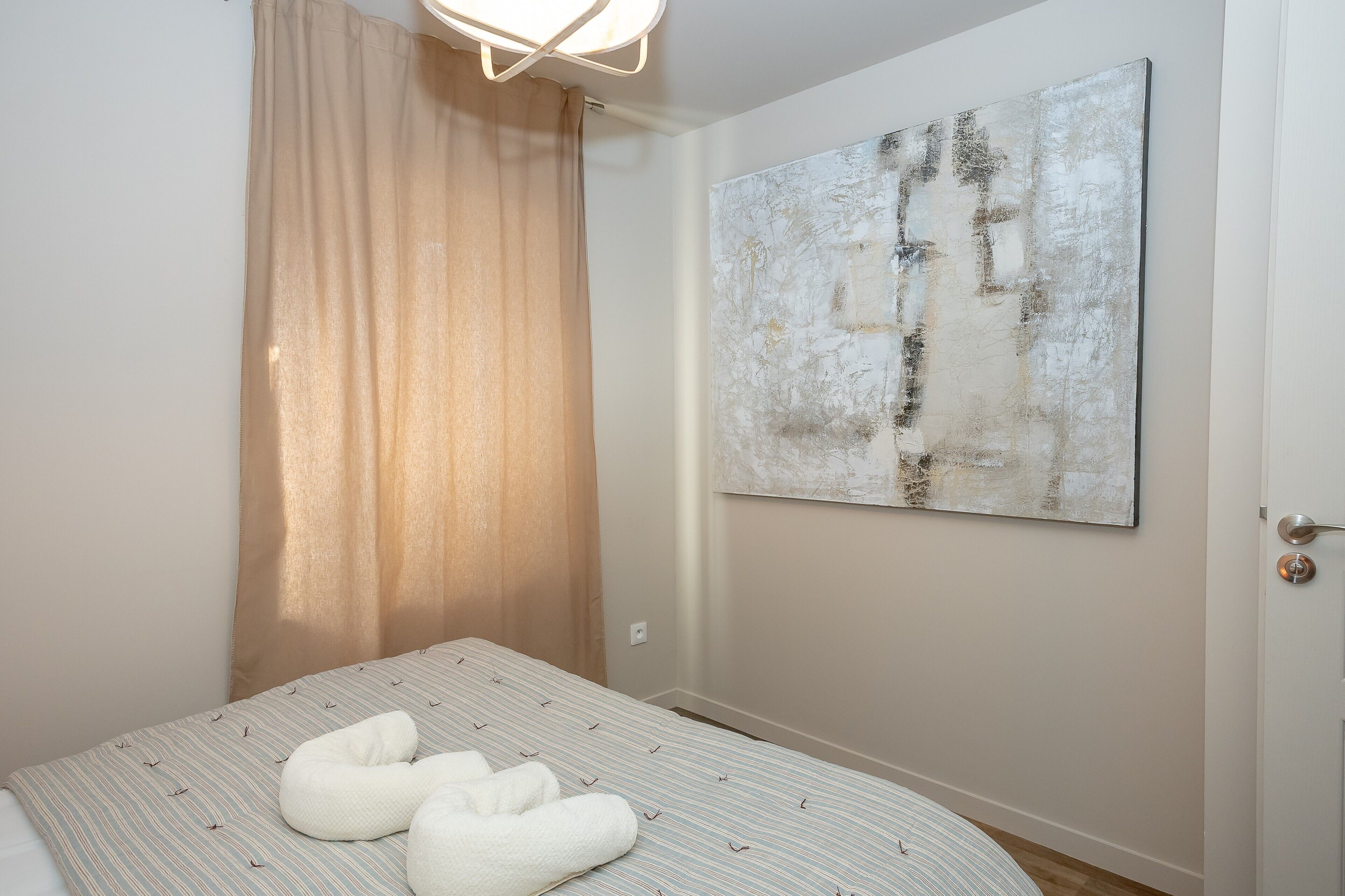 Una camera da letto con un letto, un quadro astratto di grandi dimensioni, una tenda e una porta.