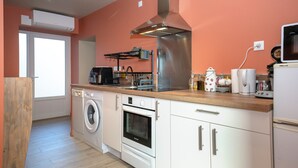 A compact kitchen with a washing machine, oven, microwave, and a coffee maker.