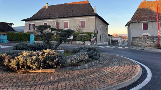 A street with buildings, a roundabout, and a sign for 'St. Andre Il Gaz.'
