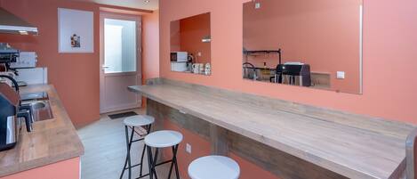 A kitchen with a wooden countertop, three white stools, a microwave, and a sink.