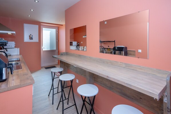 A kitchen with a wooden countertop, three white stools, a microwave, and a sink.