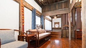 Una habitación con suelo de madera, un sofá, una silla y una lámpara colgante.