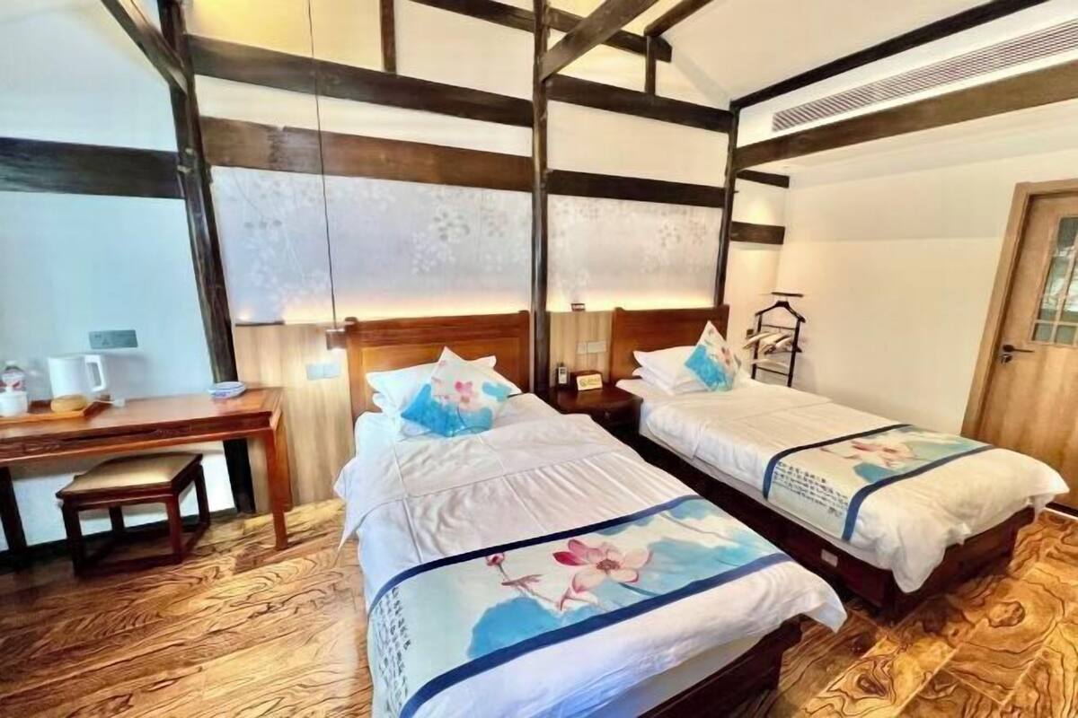 Quarto com duas camas, uma escrivaninha e uma cadeira.