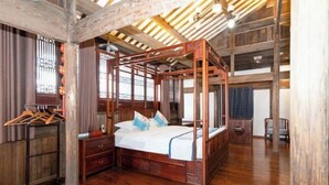 Una cama con dosel en una habitación con suelo de madera y techo inclinado.