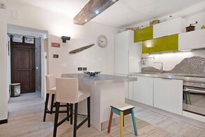Une cuisine moderne dotée d’un îlot central, de meubles blancs et d’un mur d’accent vert.