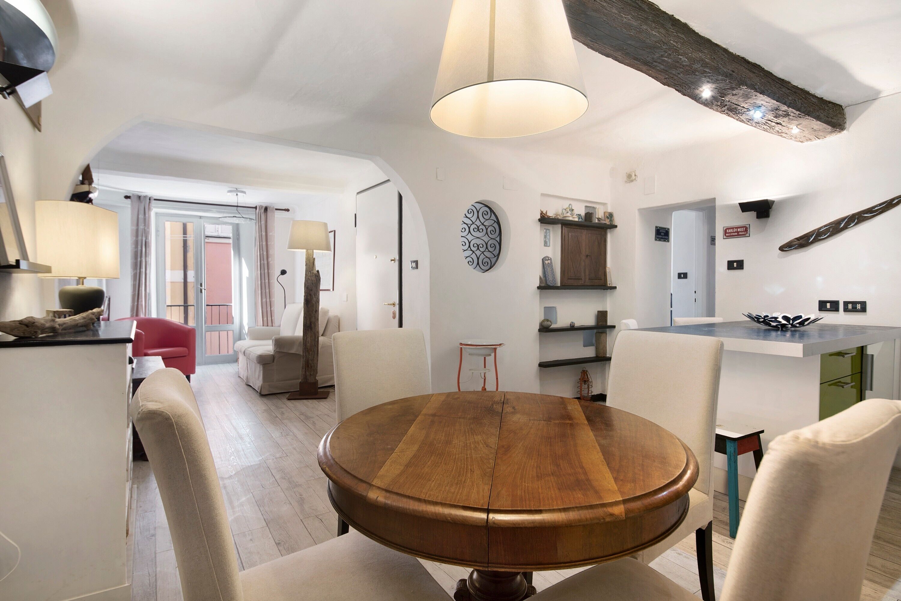Un espace repas moderne avec une table ronde en bois, des chaises blanches et un luminaire suspendu.