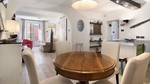 Zona de dinar moderna amb taula rodona de fusta, cadires blanques i llum penjant.