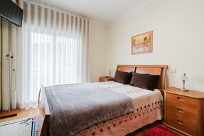 Une chambre à coucher avec un lit, des tables de chevet, une télévision et un tableau au mur.