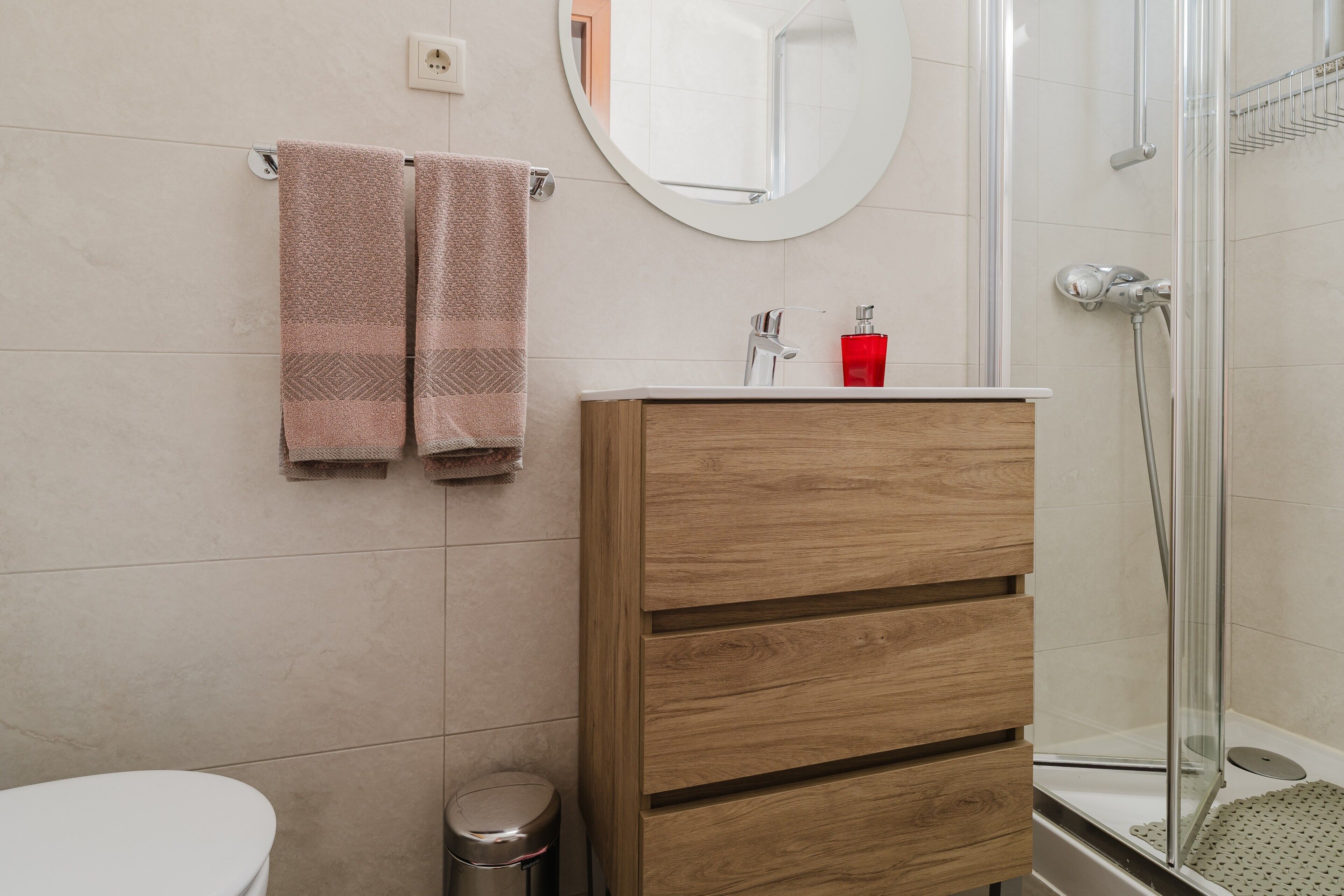 Ein Badezimmer mit Toilette, einem Holzschrank, einem Spiegel und einer Duschkabine.