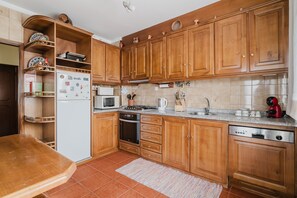 Une cuisine avec des meubles de rangement en bois, un réfrigérateur, un four à micro-ondes, une cuisinière et un lave-vaisselle.