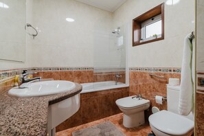 Et badeværelse med vask, badekar, toilet og bidet.
