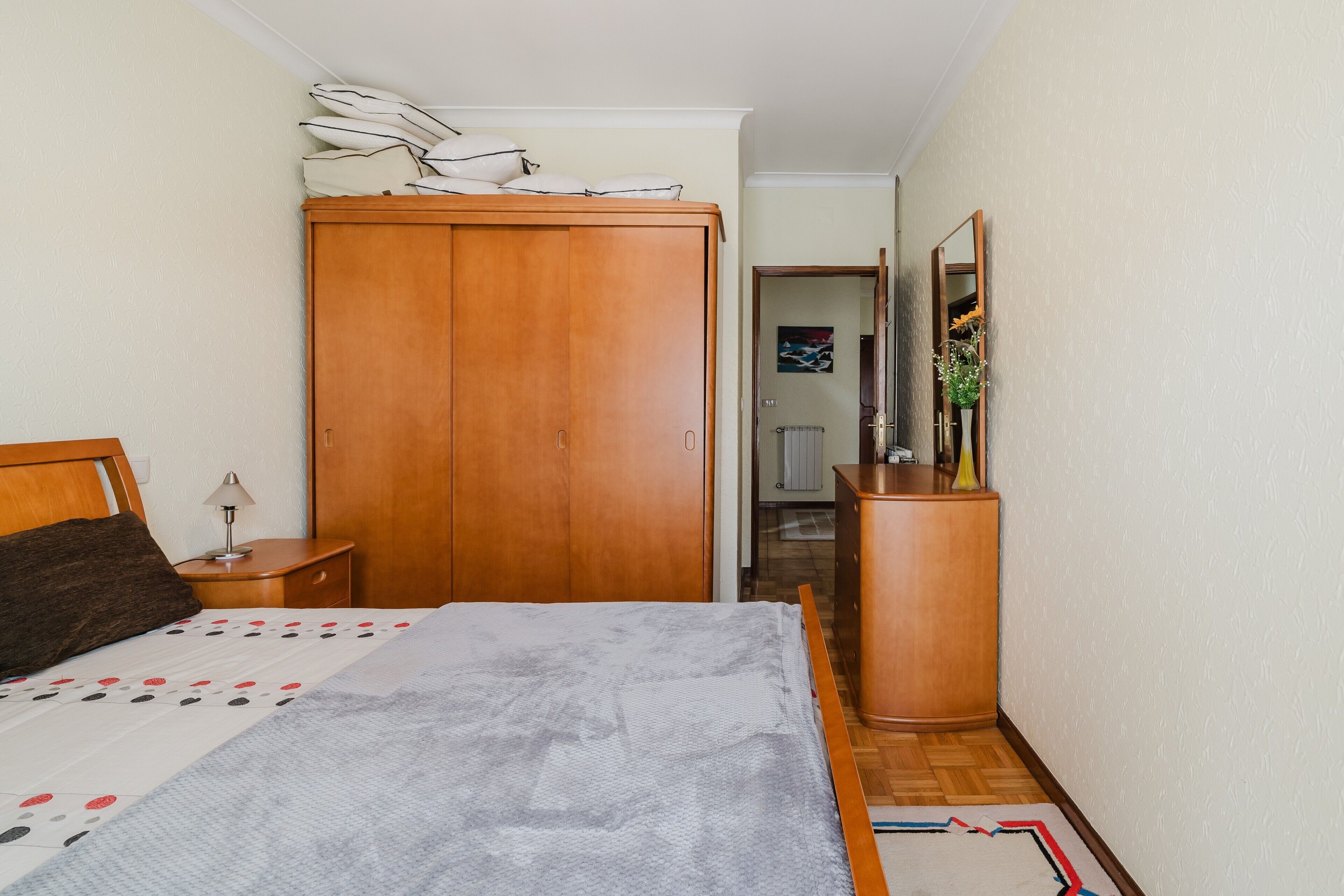 A bedroom with a bed, a wardrobe, a dresser, and a mirror.