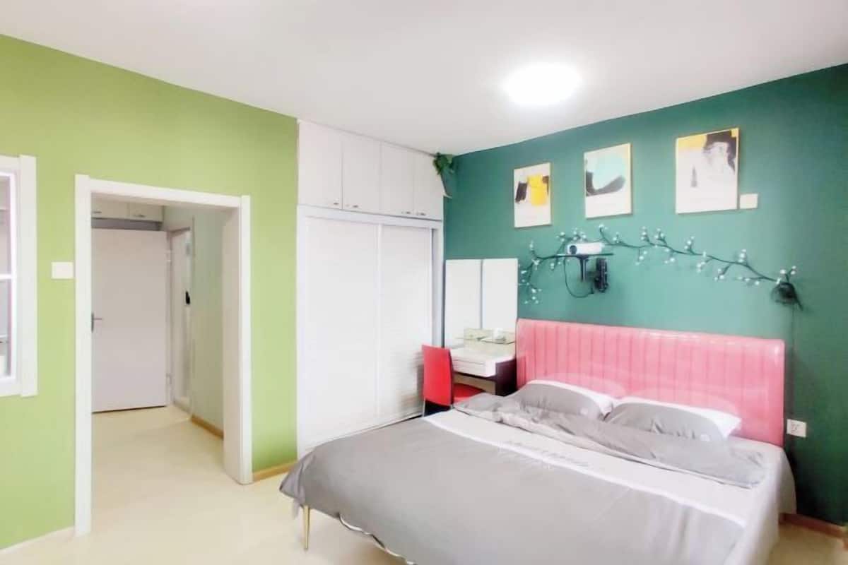 Une chambre à coucher comprenant un lit, une table de chevet, un miroir et un luminaire fixé au mur.