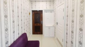 A hallway with patterned wallpaper, a wooden door, a white wardrobe, and a purple bench. - Youth Apartments (Bilberry Manor, Yichun) (Yichun)