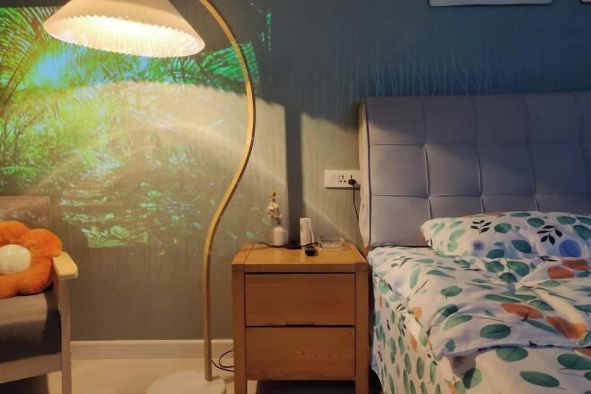 Une chambre à coucher avec un lit, une table de chevet et un projecteur mural.