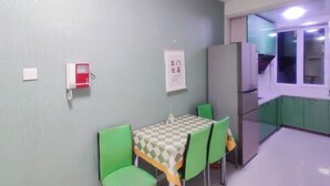 A small dining area with a table and chairs, a refrigerator, and a window. - Youth Apartments (Bilberry Manor, Yichun) (Yichun)