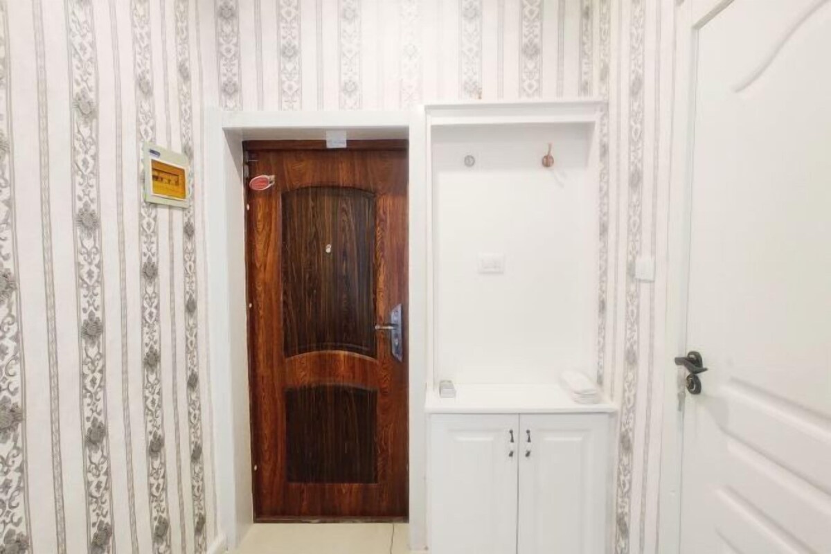 A hallway with a wooden door and a white cabinet with two doors.