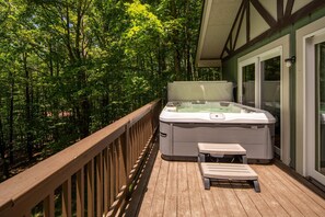 A hot tub on a wooden deck with a view of a forest.