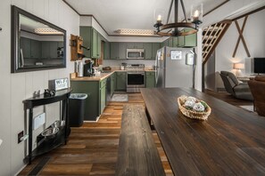 A kitchen with wooden flooring, a dining table, and a built-in microwave.