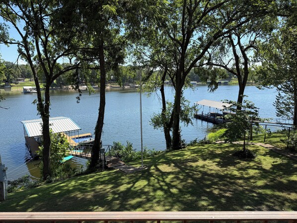 A lakeside property with a dock, grassy areas, and trees.