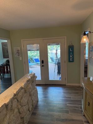 A room with a stone wall, wooden flooring, a door leading outside, and a 'LAKE' sign on the wall.
