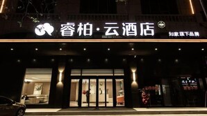 Entrada de hotel con un diseño moderno, que presenta una puerta de cristal grande y un letrero que dice 'Chop Bar - Cloud Hotel'.