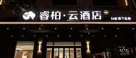 A hotel entrance with a modern design, featuring a large glass door and a sign above that reads "Chop Bar - Cloud Hotel".