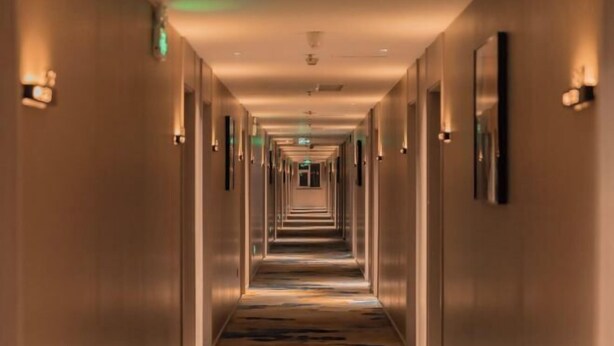 Un pasillo largo y estrecho con alfombra estampada y luces en la pared.