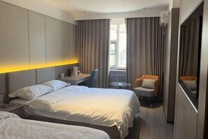 A hotel room with a large bed, a desk, a chair, and a small table.