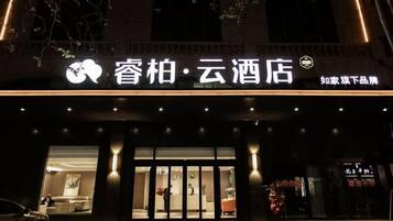 Entrada de un hotel con un cartel que muestra el nombre y una puerta de acceso visible.