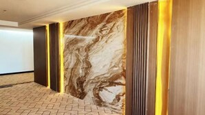 A modern hotel lobby with a marble wall, wooden paneling, and a geometric patterned floor. - Shanghai Wenfei Boutique Hotel (Shanghai)