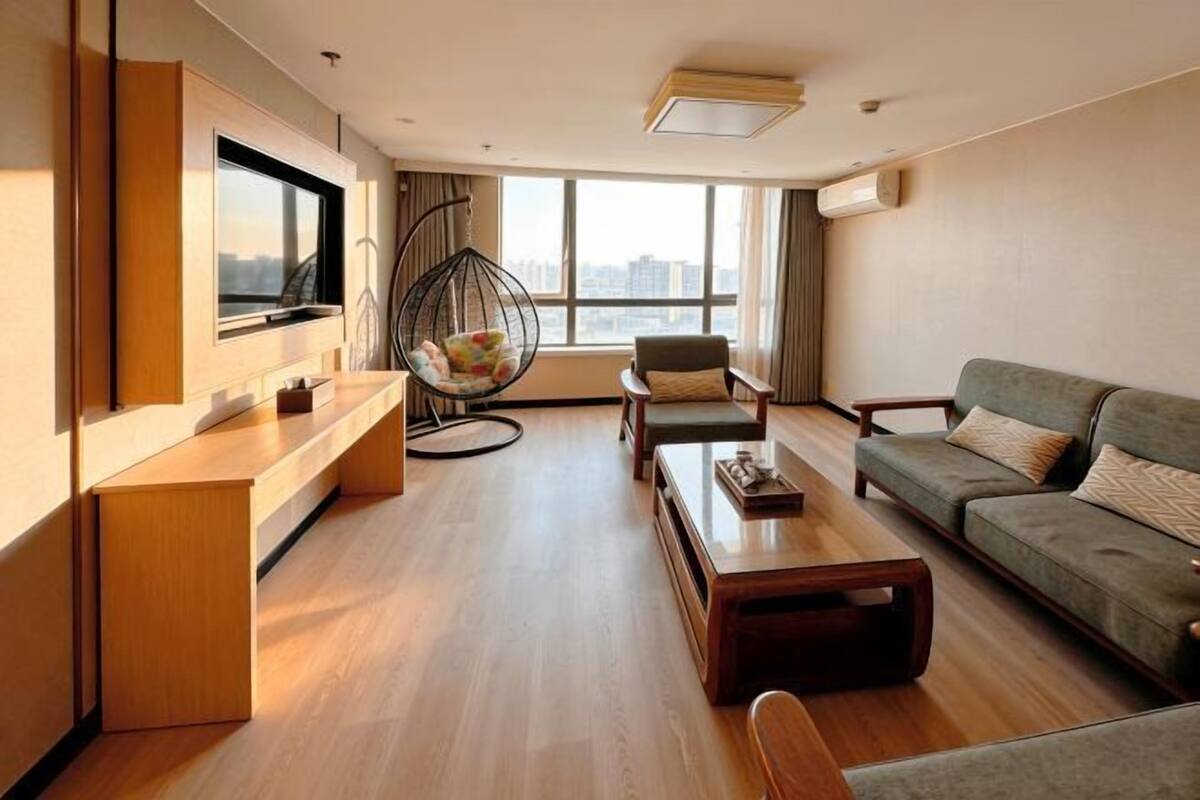 A modern living room with a TV, seating, and a city view.