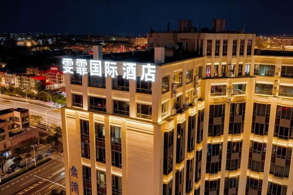 A multi-story hotel with illuminated signage, a prominent entrance, and a view of the surrounding cityscape.