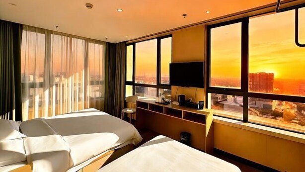 A hotel room with two beds, a desk, a chair, a TV, and a large window with a city view. - Shanghai Wenfei Boutique Hotel (Shanghai)