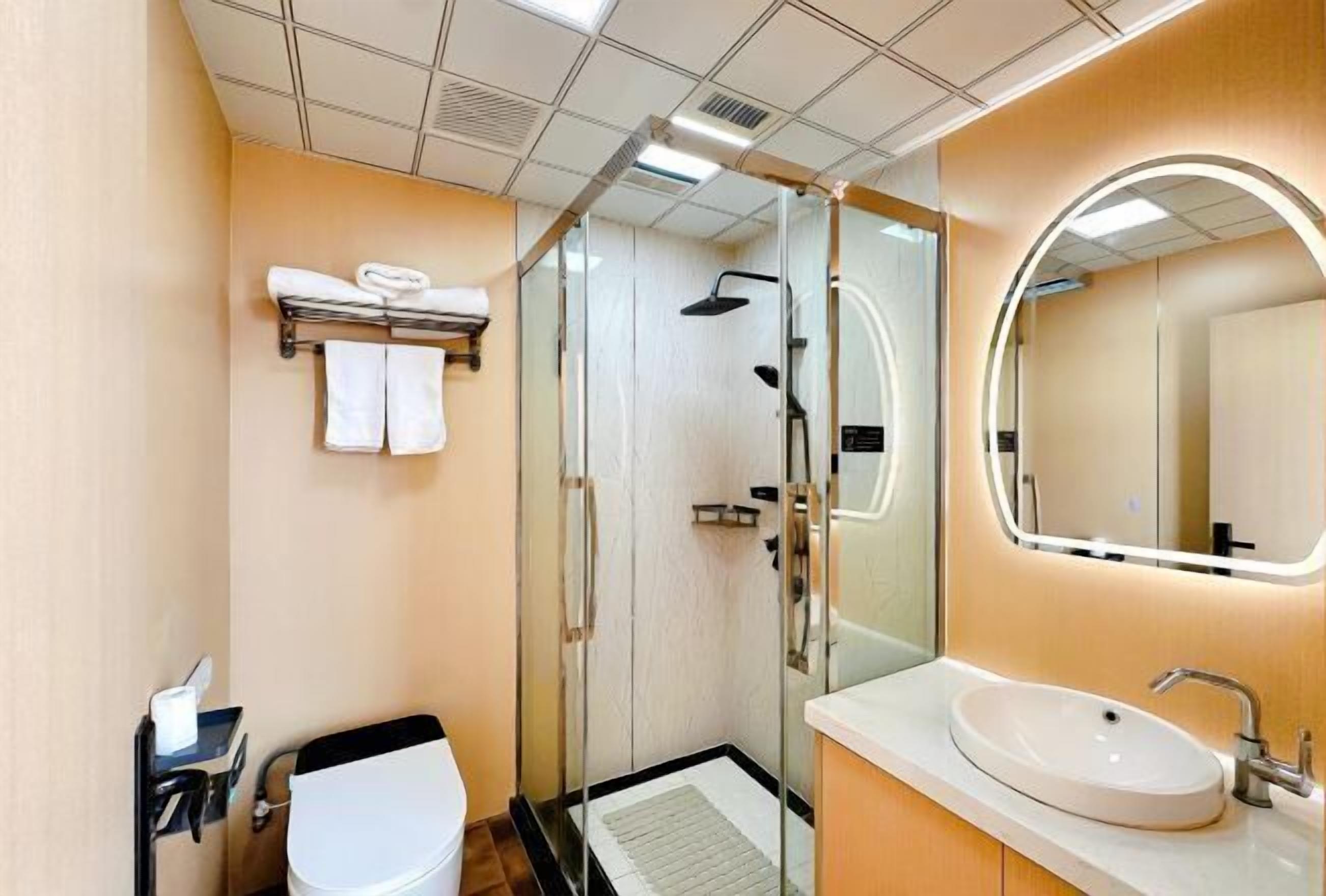 A modern bathroom with a glass-enclosed shower, a white sink, and a mirror with a circular frame.