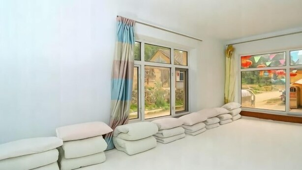 Una habitación con un ventanal grande, vistas a un jardín y una pila de toallas apoyadas en la pared.