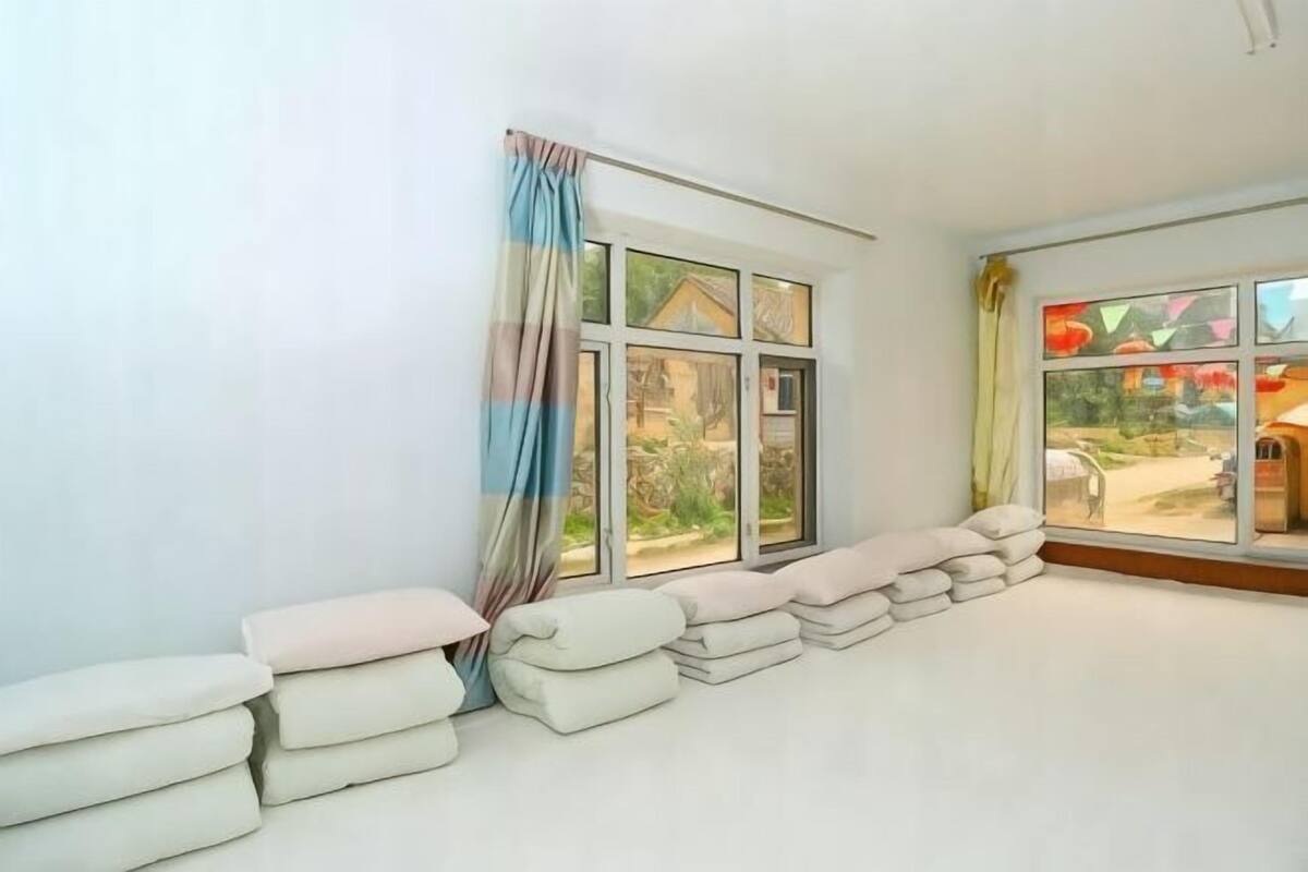 Quarto com uma janela grande, vista para um jardim e uma pilha de toalhas na parede.