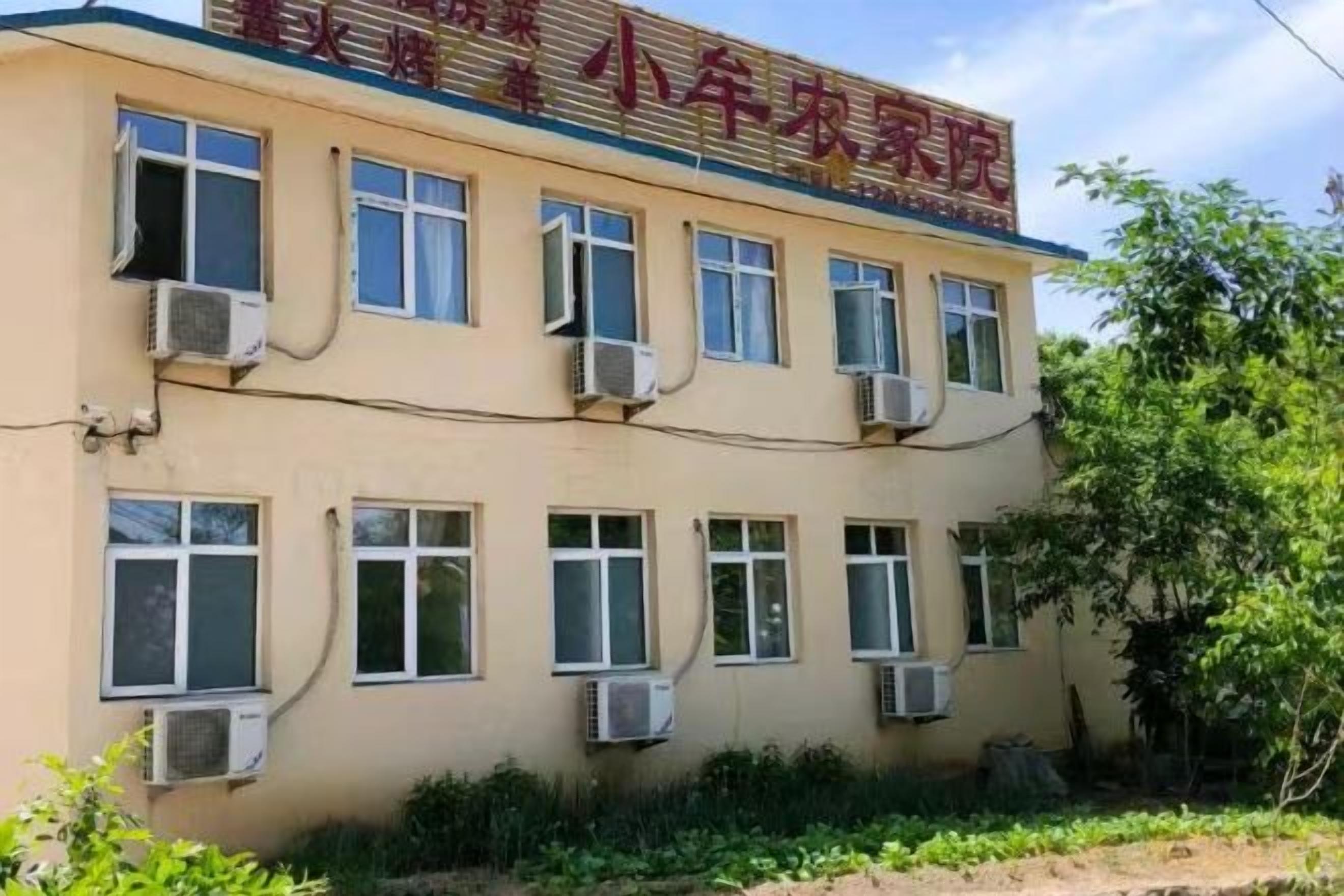 A building with multiple windows and air conditioning units, featuring a sign with Chinese characters.