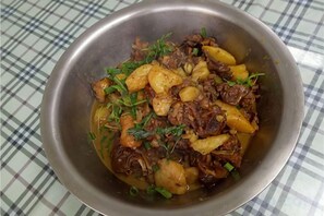 Un plato de guiso con carne y papas sobre un mantel a cuadros.
