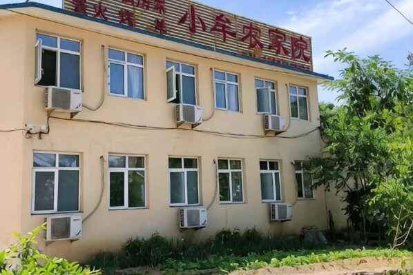 Ein Gebäude mit zahlreichen Fenstern und Klimaanlagen, umgeben von Grün.
