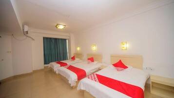 A hotel room with three beds, a desk, and a window with curtains.