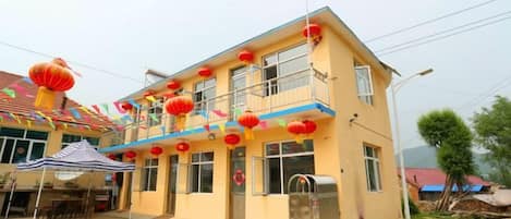 A two-story building with a balcony, a flag, and red lanterns.
